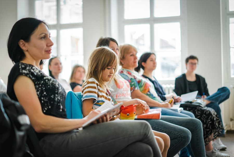 Groupe de parents assis en cercle lors d'un atelier, échangeant carnets en main